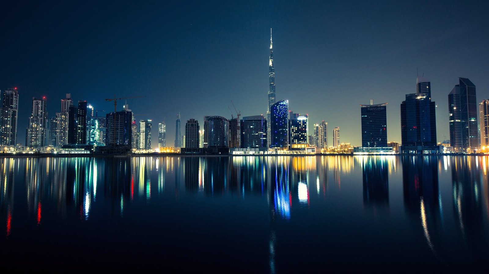 The Dubai skyline reflected across the water at dusk